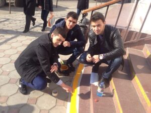 Security Ambassador to Africa Astemir Karmov is painting steps in yellow color for visually impaired people